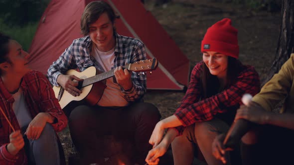 Friends at Campsite Are Singing Songs, Laughing and Cooking Food on Fire While Happy Smiling Guy Is alt