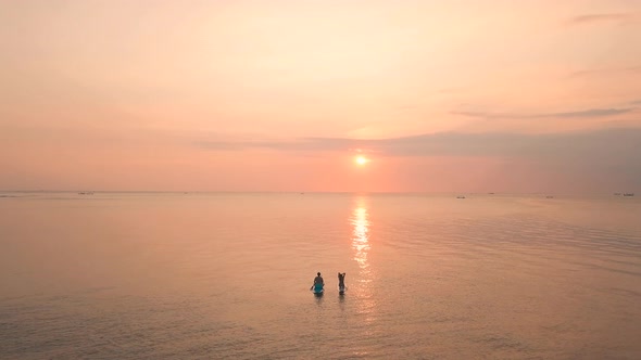 Two Young Women Enjoying an Incredible Orange Sunset in the Ocean. 