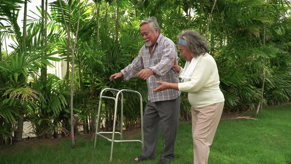 elderly man learning to walk on a walker in the garden,