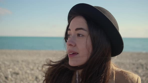 Woman Is Looking Around Sitting in Sunny Beach, Touching Hair, Close-up Portrait alt