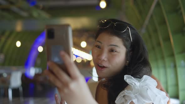 attractive asian female wear casual cloth hang around at cafe white use smartphone video calling