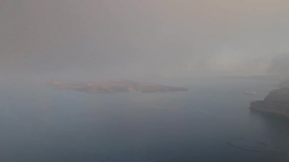 Time Lapse shot of a foggy summer morning, of the Santorini Caldera, with the volcano island visible alt
