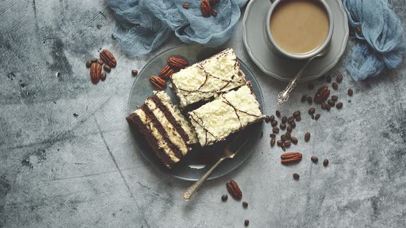 Tasty Layered Cake Sprinkled with White Chocolate. Served with Cup of Coffee on a Gray Concrete alt