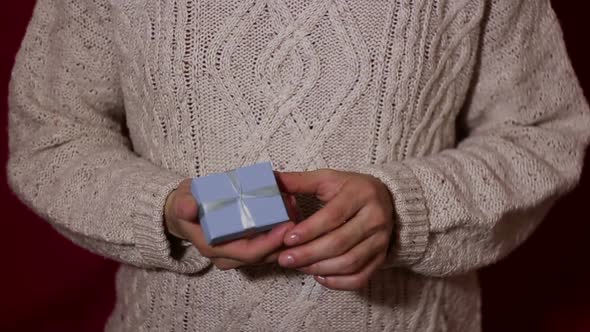 Beautiful Girl Twists a Gift in Her Hands in a Small Blue Box alt