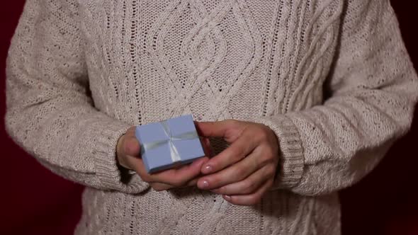 Beautiful Girl Twists a Gift in Her Hands in a Small Blue Box