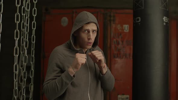 Boxer in Hoodie Throwing Punches Towards Camera alt