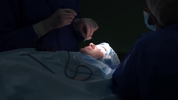 Plastic Surgeon Checking Pen Marking Dissection on Eyelid of Young Woman Lying on Surgery Bed alt