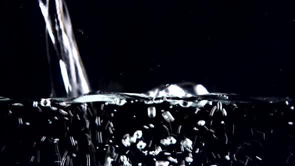 Water is poured on a black background. alt