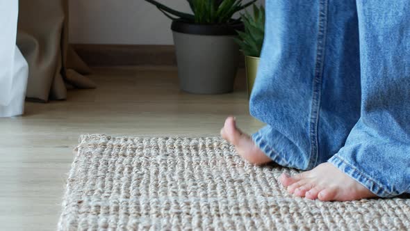 Barefoot woman  in jeans come into the frame standing on a wicker mat