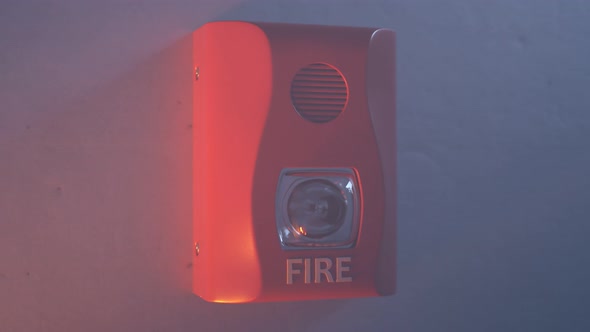 Close up shot of flashing strobe red fire alarm during fire in the room.