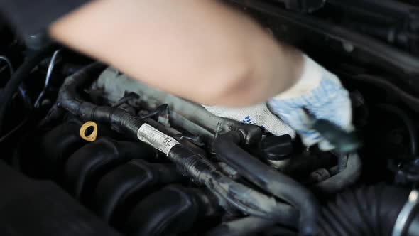 Male Auto Mechanic Changes Spark Plugs in a Car Engine