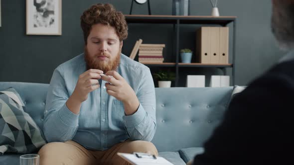 Unhappy Guy Exprerssing Sadness and Loneliness Talking to Therapist Indoors in Office alt