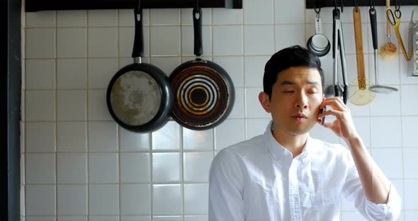 Man talking on mobile phone in kitchen 4k alt