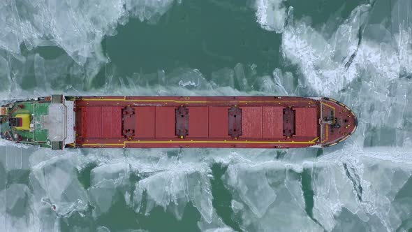 Aerial Above Epic Huge Steel Ship Breaks Ice By Bow of Ship and Floats in Large Sea Ice Floes alt
