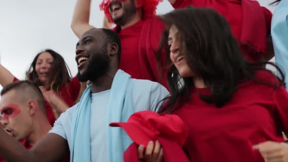 Excited group of multiracial friends watching soccer match event at stadium alt