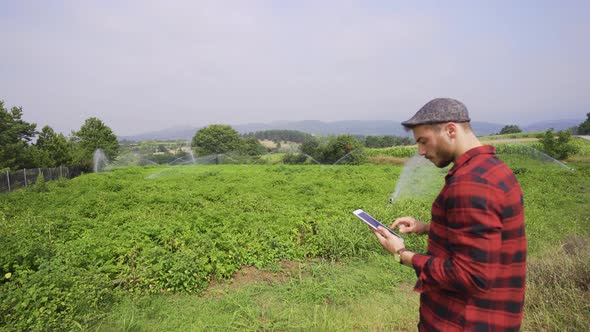 Farmer using tablet looks at his field. alt