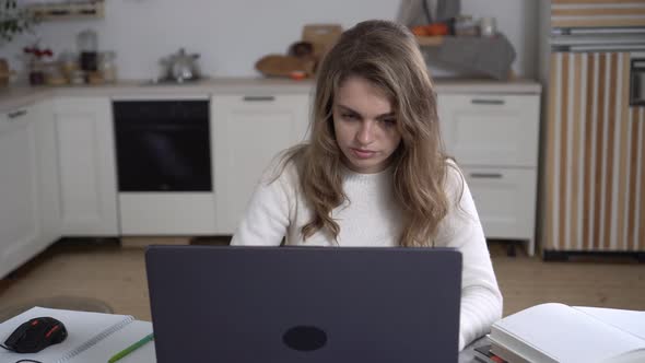 A Young Woman Works at Home with a Laptop alt