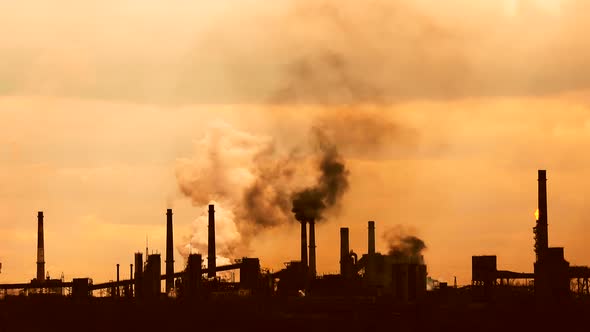 Silhouettes of factories. Fuming chimneys. Smoke, gas and steam. Metallurgical factory.