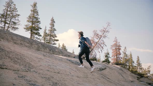 Young Beautiful Female Tourist with Backpack Hiking Alone, Climbing a Giant Rock at Yosemite alt