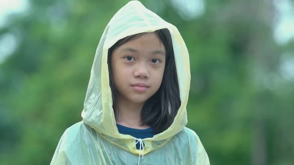 Slow motion Asian girl wearing raincoats enjoying looking at cemera, Kid playing at outdoors