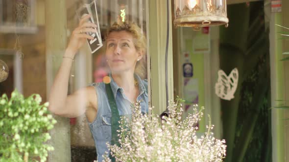 A Florist walks up to the entrance of her shop and flips the sign to open, beginning a day of succes