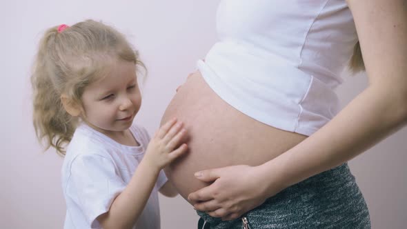 Girl Kisses Large Tummy of Pregnant Mummy Listening To Baby alt