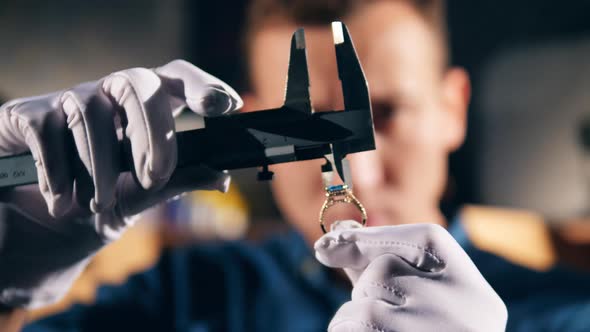 Jeweller, Goldsmith Measures a Gemstone on a Ring. alt