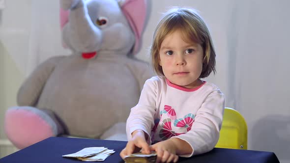 A small child recounts and shifts the notes on the children's table.