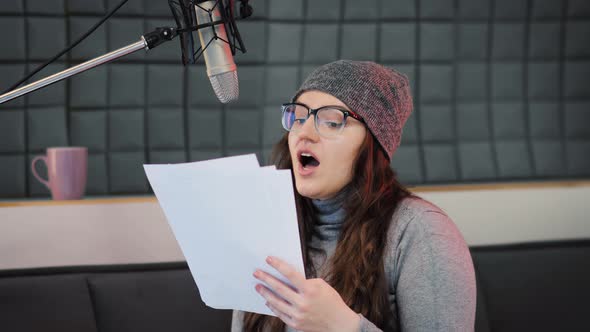 A female voice actor recording animated voices into a professional microphone alt