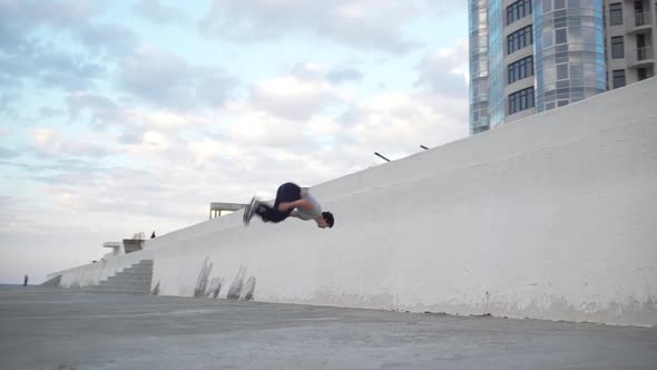 Caucasian Male Gymnast Performing Serie of Acrobatic Exercises Using Wall and Parapet in Slowmotion alt