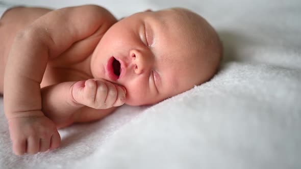 Cute emotional newborn yawning funny little baby boy sleeping in crib. Infant baby. Nursery