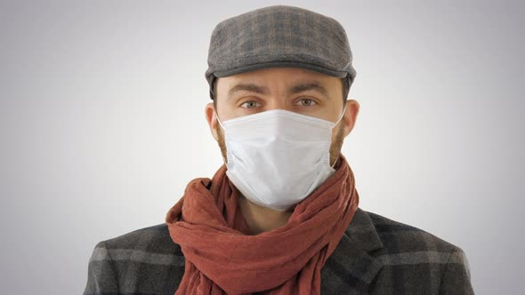 Handsome Young European Man in Trendy Coat Wearing Disposable Protective Face Mask on Gradient alt