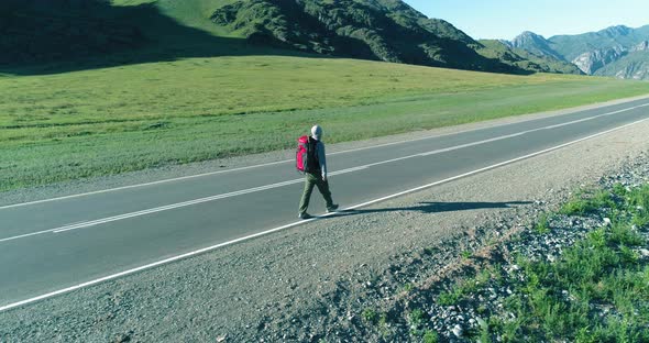 Flight Over Hitchhiker Tourist Walking on Asphalt Road alt