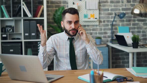Mad Young Man Yelling on Mobile Phone Gesturing Working in Office Alone alt