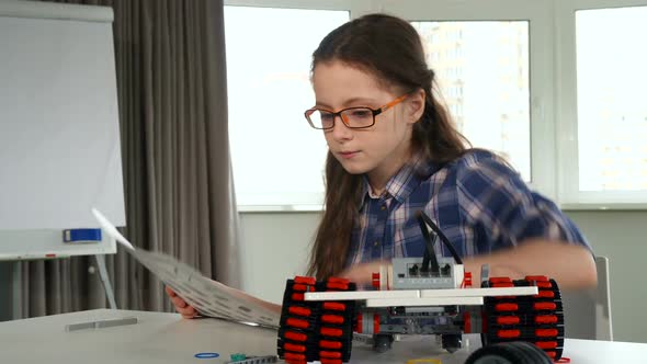 Little Girl Explores the Instruction of Construction Set alt