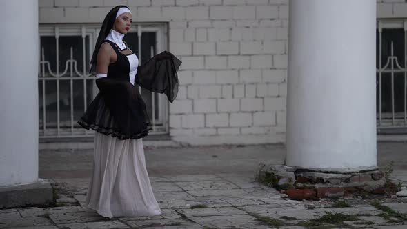 Sexy Lady is Wearing Erotic Suit of Catholic Nun Woman is Walking Near Old Monastery alt