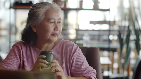 Senior woman happily with hot coffee in coffee shop