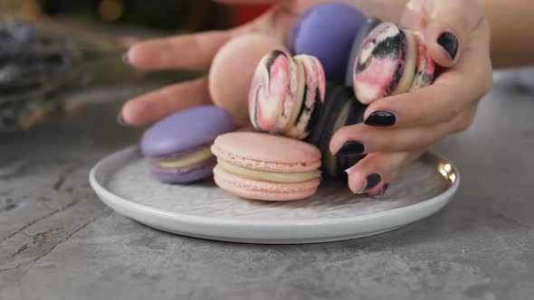 Female Chef Hands Putting Macaroons Into the Plate alt