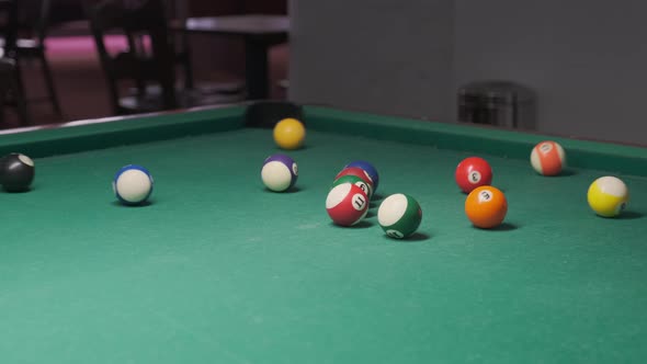 an initial strike in a pool game on a green pool table cloth. snooker game.