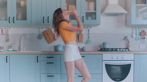 A Beautiful Woman in White Shorts is Relaxing at Home Dancing in the Kitchen alt