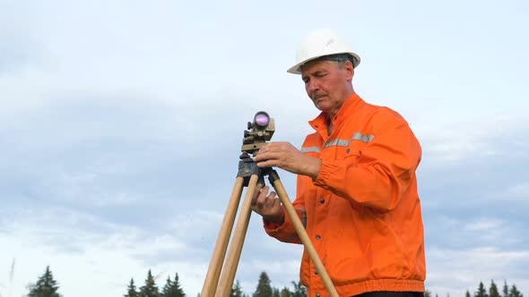 Skilled Surveyor Fixes Dumpy Level on Brown Wooden Tripod alt