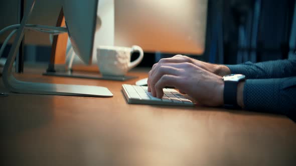 Man Typing On Keyboard At Night. Creative Man With Computer Working At Open Space Room On Night. alt