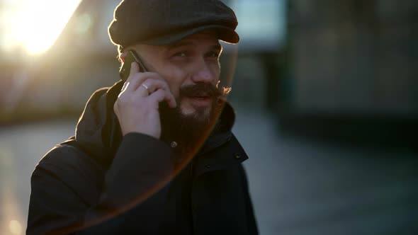 Portrait of a Mustachioed and Bearded Man in a Cap in the Contrasting Sunlight alt