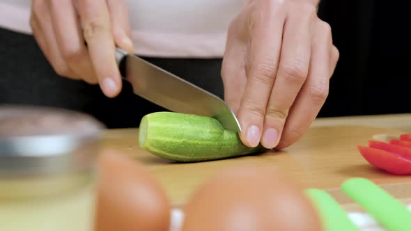 Woman's hands using kitchen knife cutting fresh cucumber for making healthy sandwich alt