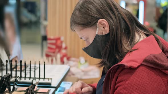 Girl in a Medical Mask Buys Cosmetics in a Shop