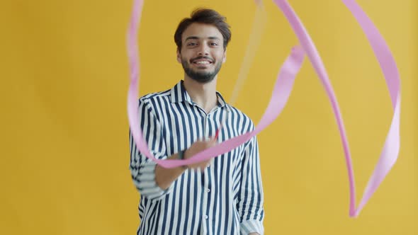 Playful Arab Man Dancing and Waving Artistic Gymnastics Ribbon on Yellow Background alt
