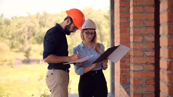 Two Engineer In Helmet Inspecting Building. Civil Architect Checking Construction. Building Project. alt