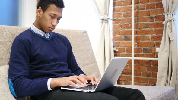 Young African Man Working on Laptop at Night alt