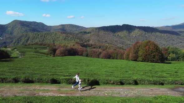 Girl with Her Son Run on the Tea Plantation