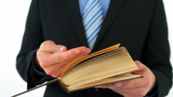 Mid-section of businessman flipping pages of book alt